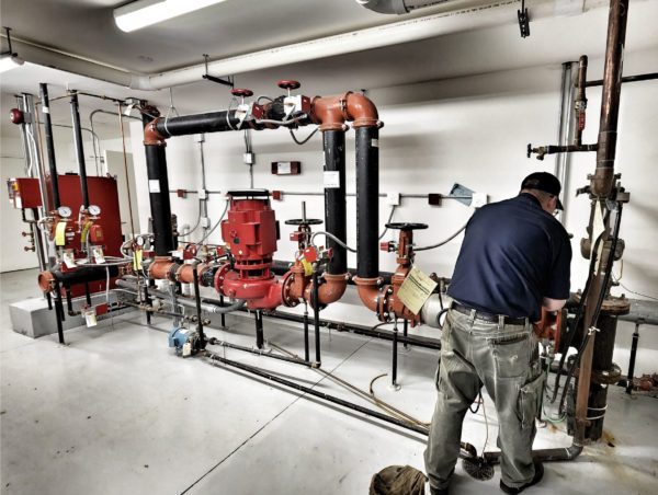 A certified backflow tester repairing a large backflow device